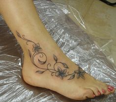 a woman's foot with flowers and vines on the bottom part of her leg