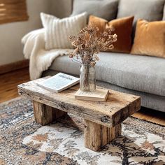 a wooden table sitting on top of a rug in front of a couch and coffee table