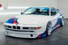 a white car with blue and red stripes on it's hood is parked in a garage