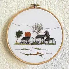 a cross stitched picture of a house in the snow with trees and mountains behind it