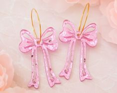 These pink sequin bow earrings are the perfect accessory to add an extra pop to your outfit! Acrylic is very lightweight so you can enjoy large, statement earrings comfortably all day. ♡ Made with pink sequin acrylic ♡ Size: Approximately 2.5 inches in length measured from earring hoop  ♡ Choice of 18k gold plated brass or stainless steel earring hoop ♡ Care Instructions: ♡ - To clean: Wipe with a microfiber cloth to remove any dust - Avoid contact with perfumes and lotions as these can react with acrylic and cause discoloration in some cases. We recommend putting on your earrings after getting ready - Although acrylic jewelry is durable, it is still a delicate material. We recommend storing them on a jewelry stand or box when not in use. - Avoid wearing or submerging in water, please don' Pink Bow Jewelry For Party, Pink Party Jewelry With Bow Detail, Pink Ribbon Jewelry For Party, Elegant Pink Bow Earrings For Party, Pink Bow Jewelry For Valentine's Day Party, Valentine's Day Pink Bow Jewelry For Party, Valentine's Day Party Jewelry With Pink Bow, Pink Bow Earrings In Cute Style, Cute Pink Earrings With Pink Bow