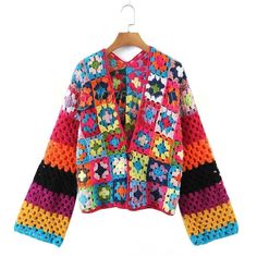 a colorful crocheted jacket hanging on a wooden hanger with a white background