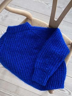 a blue sweater sitting on top of a wooden chair