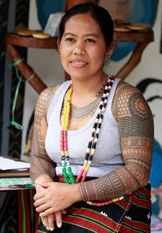 a woman with tattoos on her arms and chest is sitting in front of a table