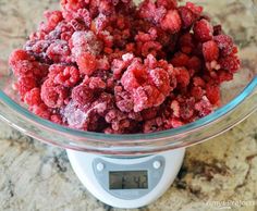 a glass bowl filled with raspberries on top of a scale