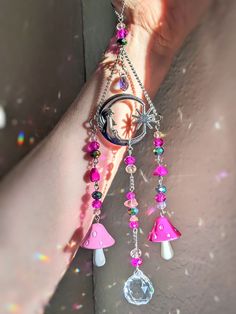 a woman's hand holding onto a pink and white necklace with charms on it