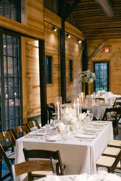 the tables are set with white flowers and candles for an elegant wedding reception in a log cabin