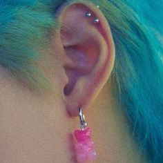 a woman with blue hair wearing pink ear piercings