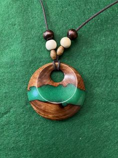 a wooden necklace with green and white beads on it's cord, sitting on a green surface