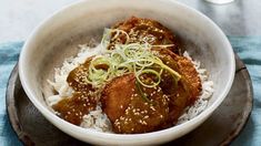 a bowl filled with rice and meat covered in sauce