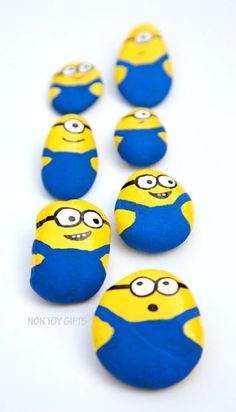 several blue and yellow minion rocks are arranged in a row on a white surface