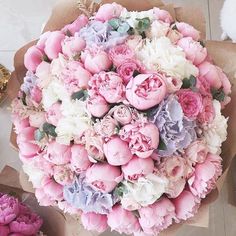 a bouquet of pink and white flowers sitting on top of a table next to other flowers