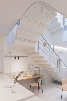 a room with some chairs and a table under a stair case next to a staircase