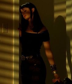 a woman is standing in the shadows with her hand on her hip and looking off into the distance