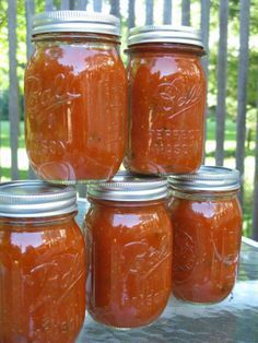 four jars filled with red liquid sitting on top of a table