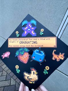 someone is holding up a graduation cap with pixel art on it and an award plaque