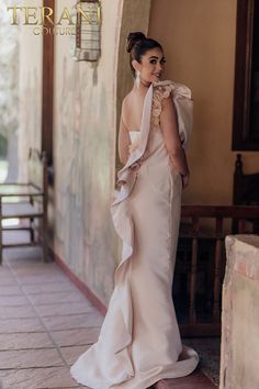 a woman in a wedding dress standing on the side of a building with her back to the camera