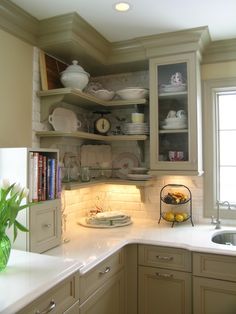 a kitchen filled with lots of white counter tops and cupboards next to a window