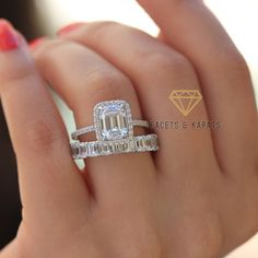 a woman's hand holding an emerald and diamond ring with two rows of diamonds on it