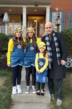 two adults and two children standing in front of a house wearing matching outfits for halloween