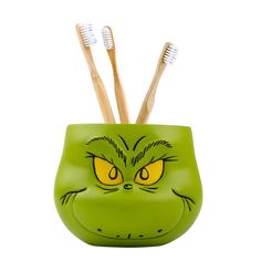 toothbrush holder with green cat face and yellow eyes on the front, white background