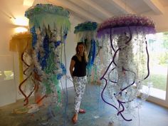 a woman standing in front of three jellyfish sculptures