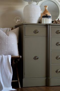 a dresser with several drawers in front of a mirror and lamp on top of it