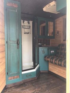 the inside of a bathroom with wood floors and green walls, including a shower stall