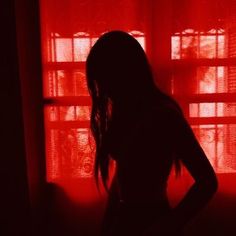 the silhouette of a woman standing in front of a red curtain with her hands on her hips