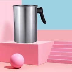 a pink and blue background with a large metal coffee mug sitting on top of a block