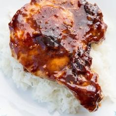 a white plate topped with meat covered in gravy on top of rice and sauce