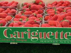 several baskets of strawberries sit in front of a sign for garignette