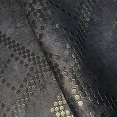 an upholstered black and gold fabric with hexagonal design on it's surface