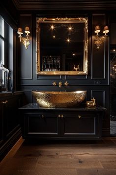 an elegant bathroom with black walls and gold fixtures on the sink, along with dark wood flooring