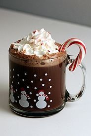 there is a hot chocolate drink with whipped cream and candy canes in the cup