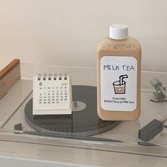 a bottle of milk sitting on top of a table next to a clock and calendar