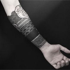 a person's arm with a black and white tattoo design on the left forearm