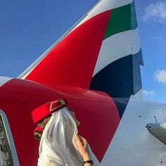 a woman standing next to an airplane with the tail end painted red, white and blue