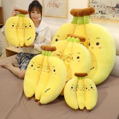 a woman sitting on top of a bed next to bunches of banana shaped pillows