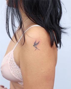 a woman with a small bird tattoo on her back shoulder and arm, behind her is a white bra