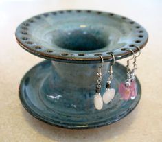 a small blue vase with earrings hanging from it