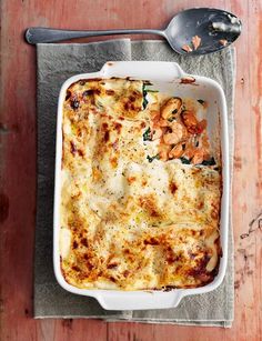 a casserole dish with chicken, spinach and cheese in it next to a spoon