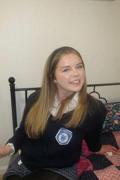 a young woman sitting on top of a bed next to a black metal headboard