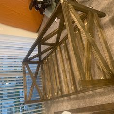 a wooden lantern hanging from the ceiling in front of a window with blinds on it