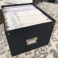 an open file box with files in it on a carpeted area next to a bed