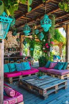 an outdoor living area with wooden pallets and colorful pillows on the couches, potted plants hanging from the roof