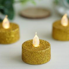 three gold glitter candles sitting on top of a table