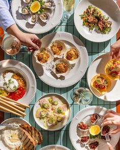 several plates of food on a table with chopsticks and drinks in front of them