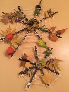 a spider web made out of leaves and twigs with autumn colors on the top part