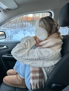 a woman sitting in the back seat of a car with her head resting on a pillow